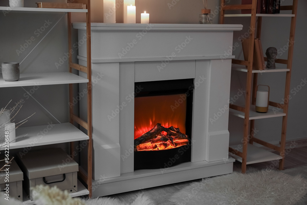 Interior of modern living room with fireplace, burning candles and shelving units