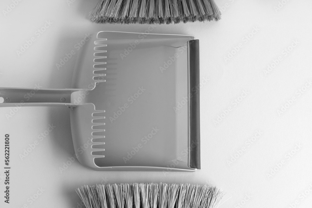 Dustpan and cleaning brushes on light background