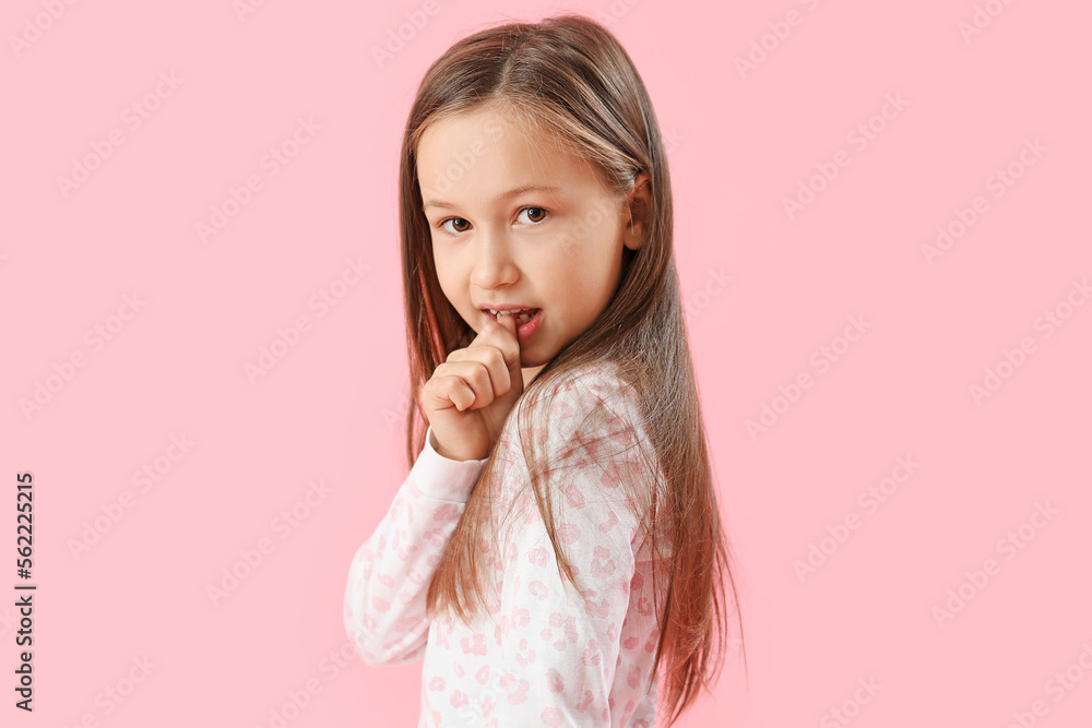 Little girl biting nails on pink background