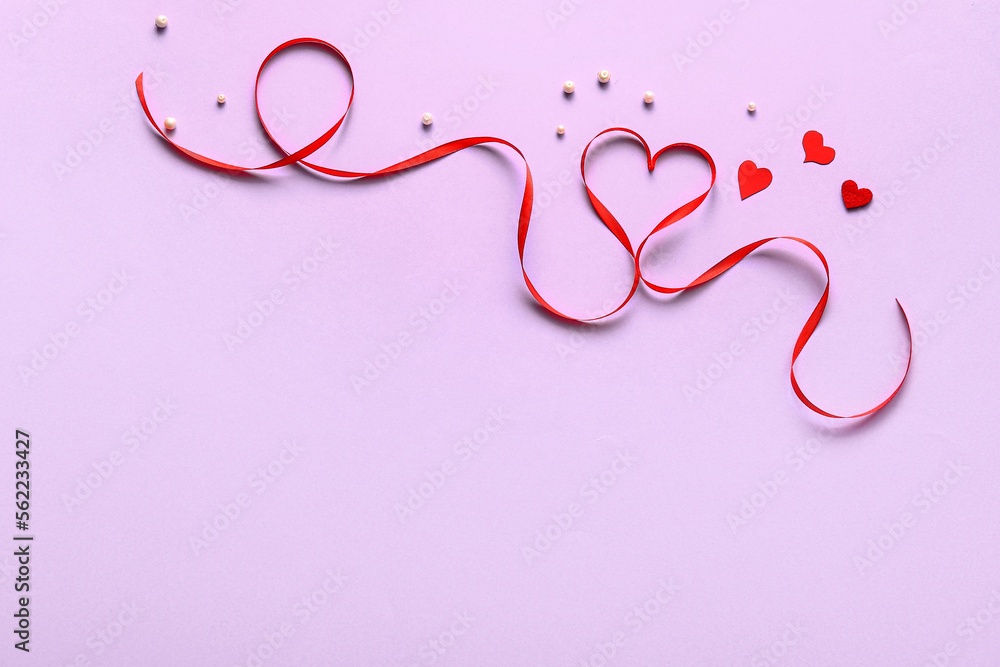 Red ribbon with hearts and beads on lilac background. Valentines Day celebration