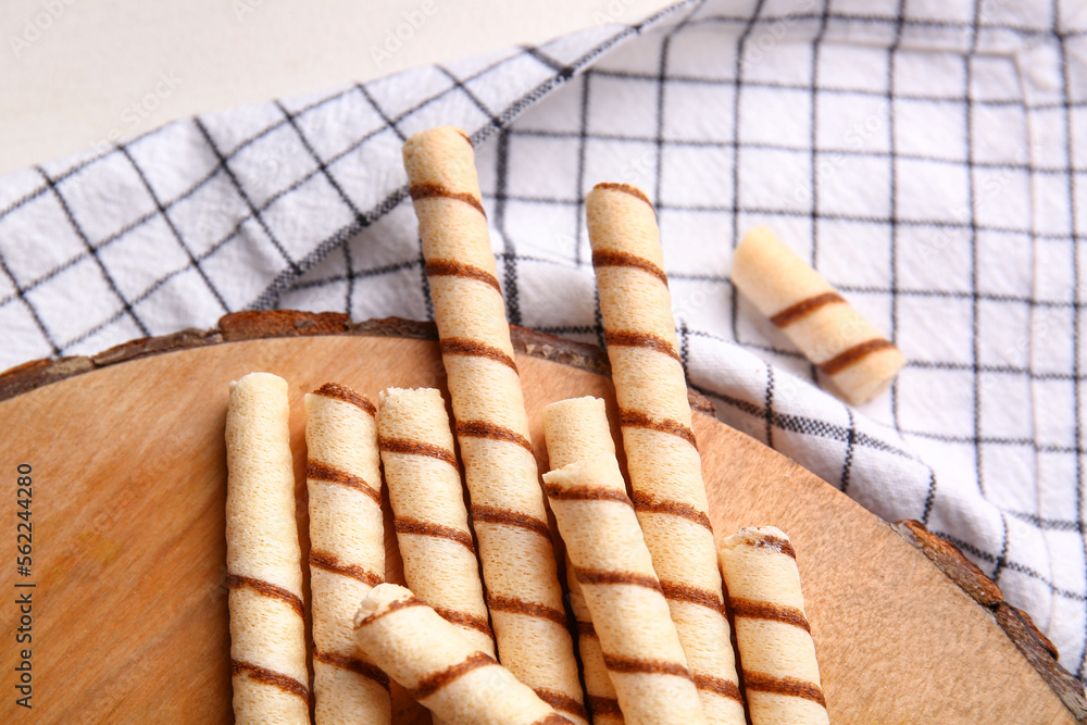 Cutting board with tasty wafer rolls and kitchen towel on table