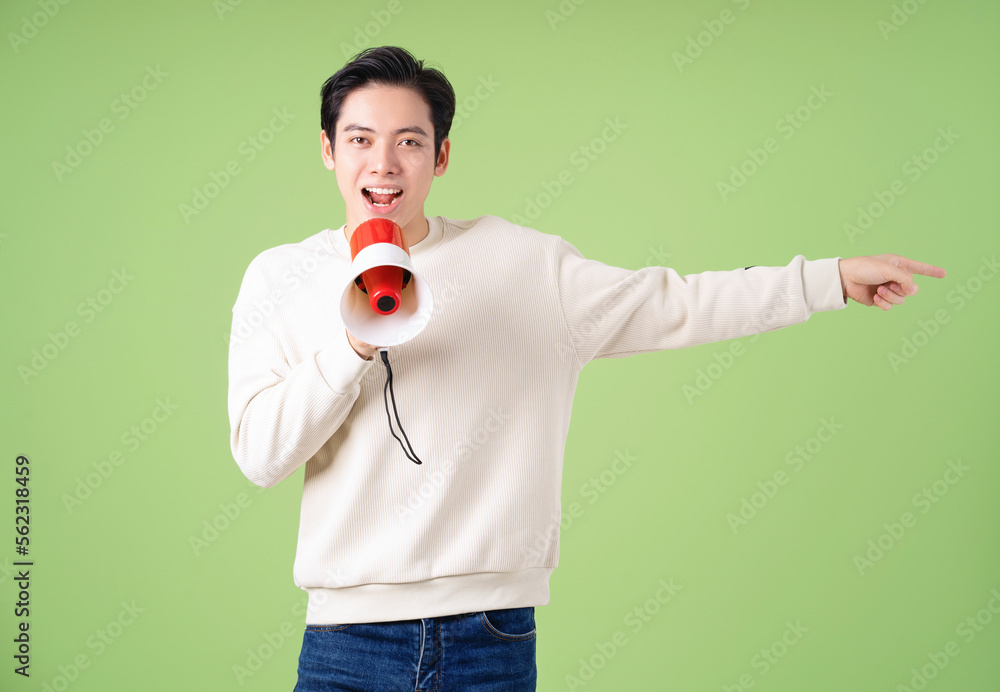 Image of young Asian man holding speaker on background