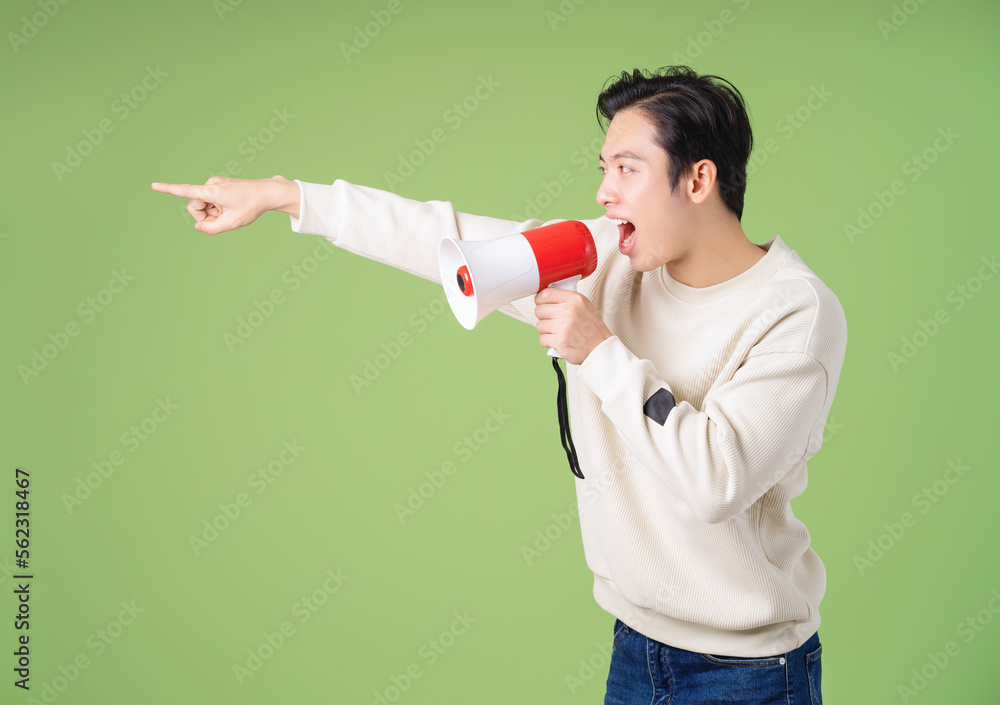 Image of young Asian man holding speaker on background