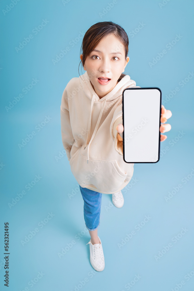 Full length image of young Asian girl using smartphone