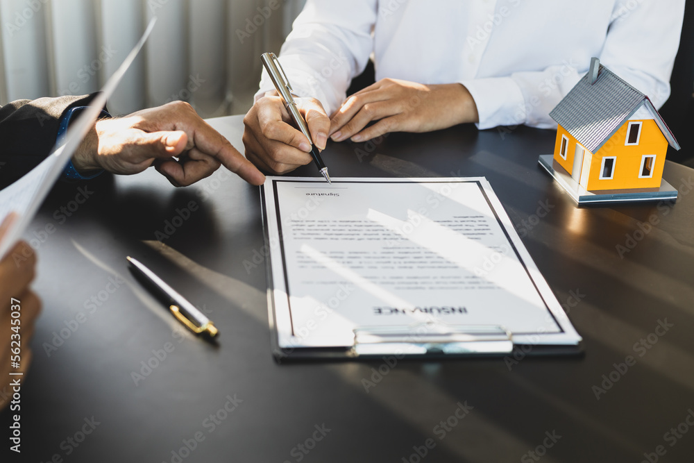 Businessman in suit in his office showing an insurance policy and pointing with a pen where the poli