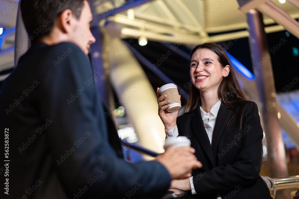 Caucasian young businessman and woman stand outdoor in city at night. 