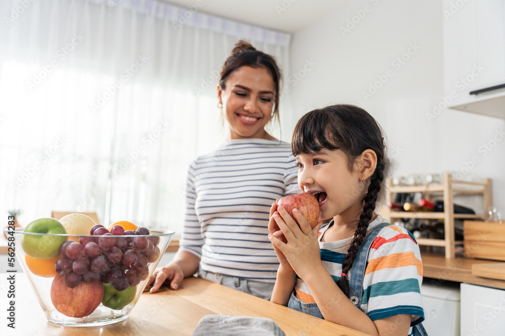 高加索小孩和妈妈在厨房里咬苹果。