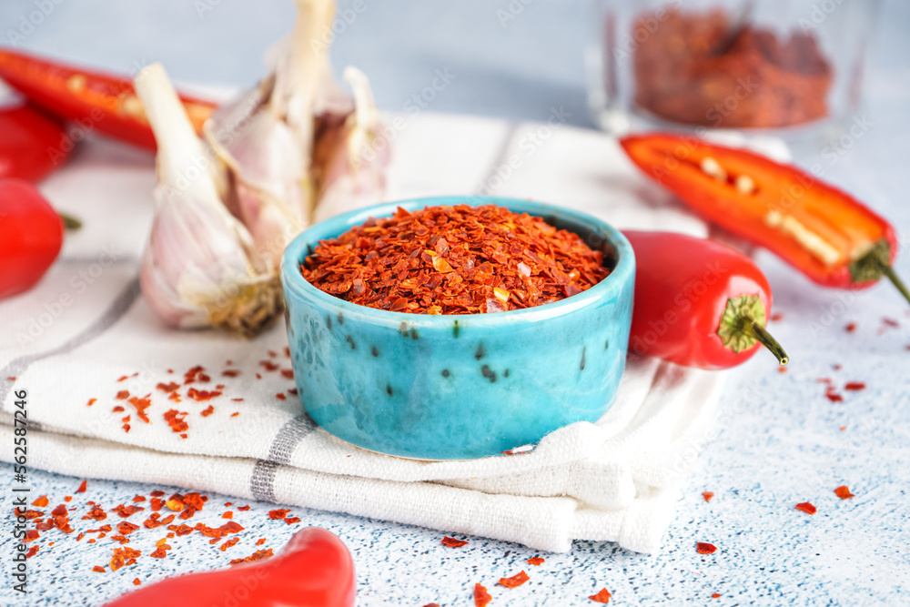 Bowl with chipotle chili flakes on light background