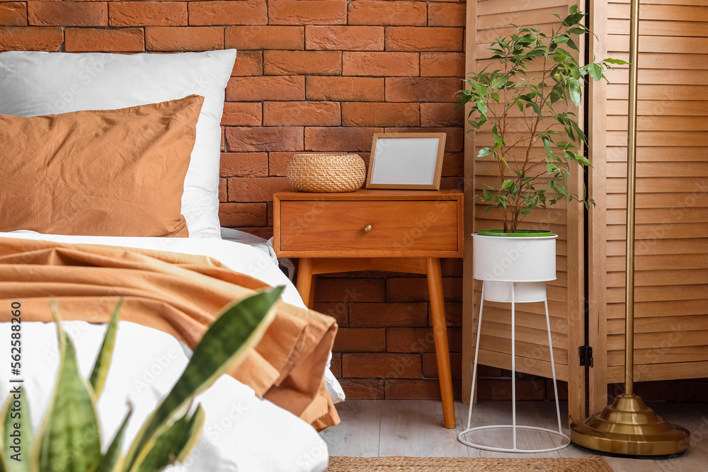 Bedside table with basket and photo frame in interior of modern bedroom