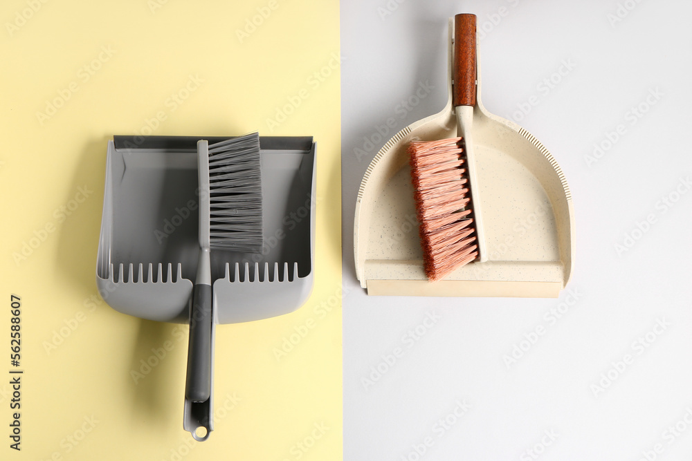 Dustpans and brushes on color background