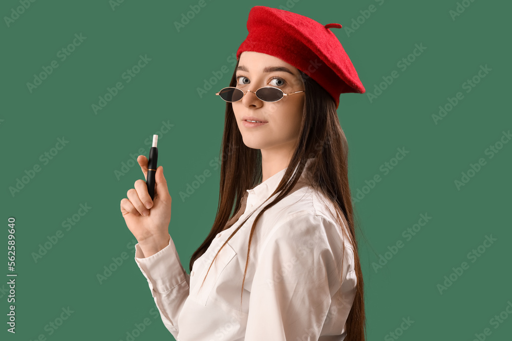 Stylish young woman with disposable electronic cigarette on green background, closeup