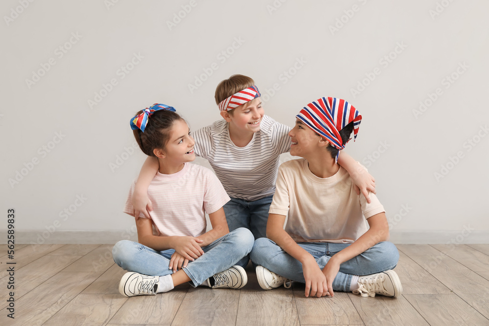 Happy little friends sitting near grey wall