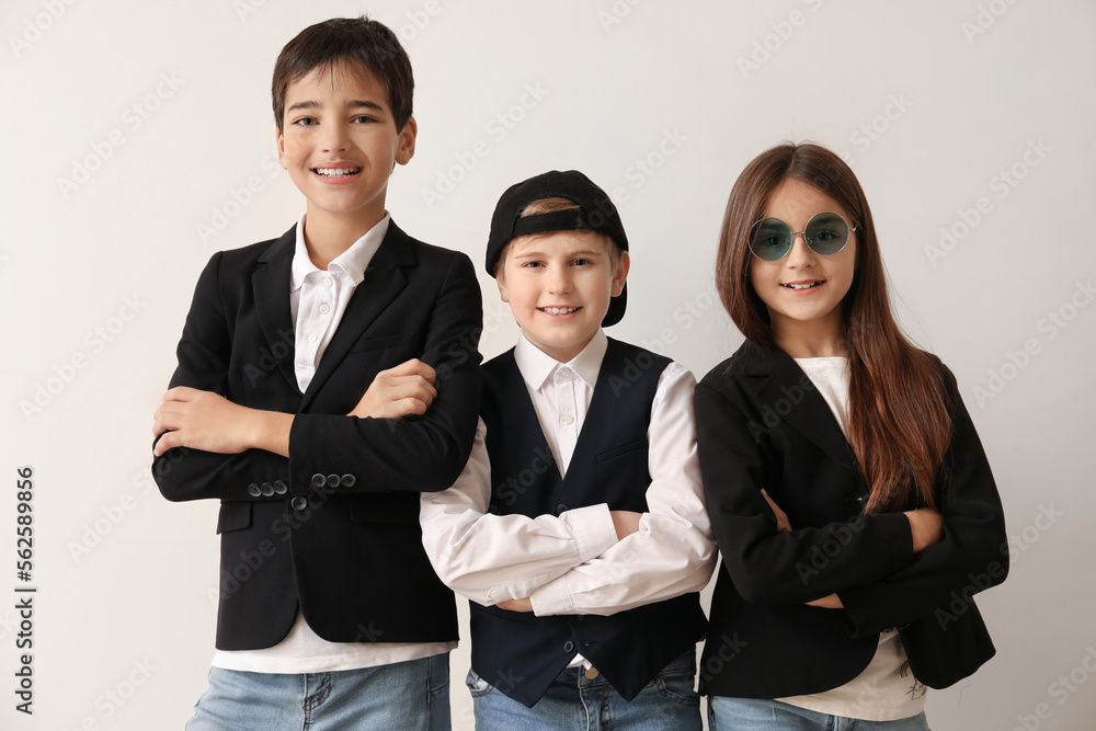 Little friends in stylish school uniform near light wall