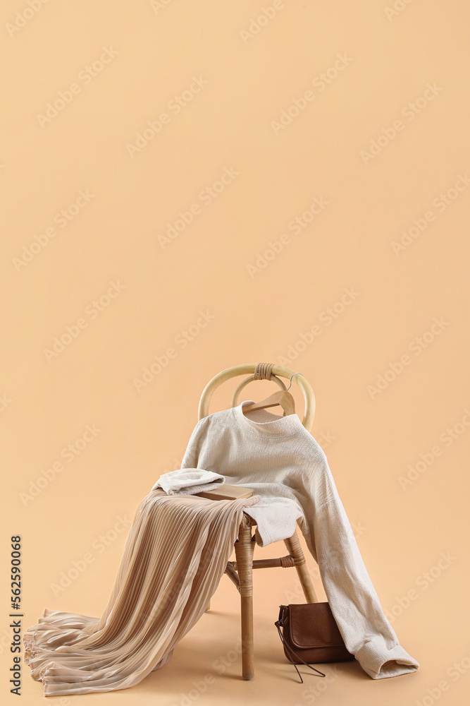 Chair with stylish clothes, book and bag on beige background