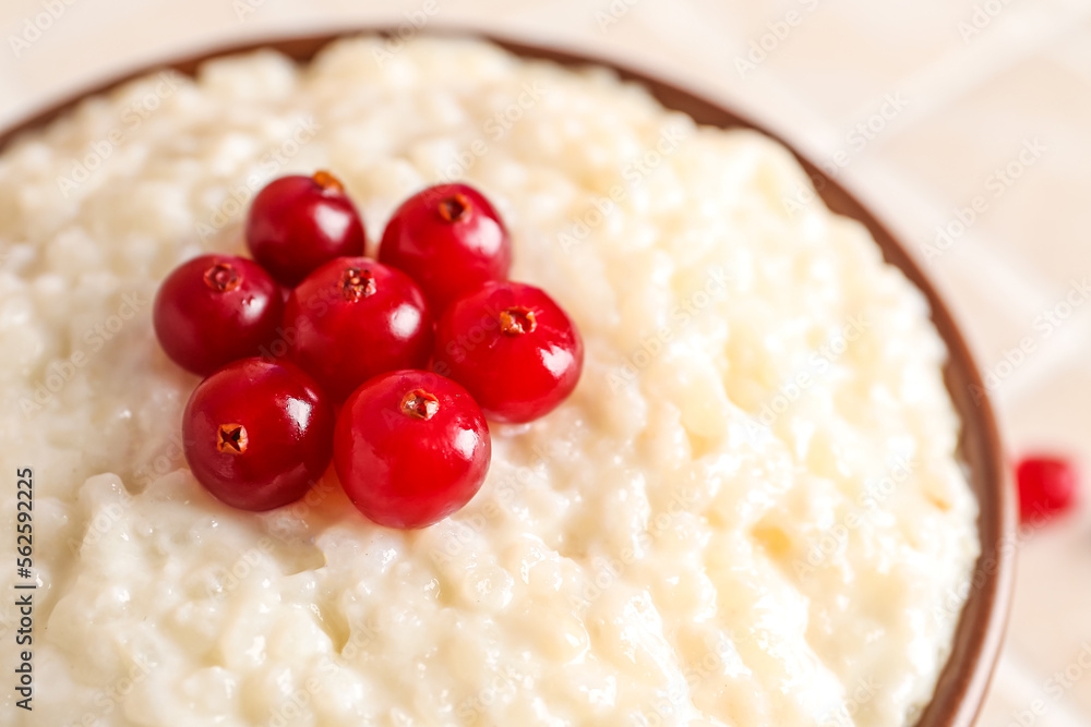 Bowl with delicious rice pudding and cranberries on tile table, closeup