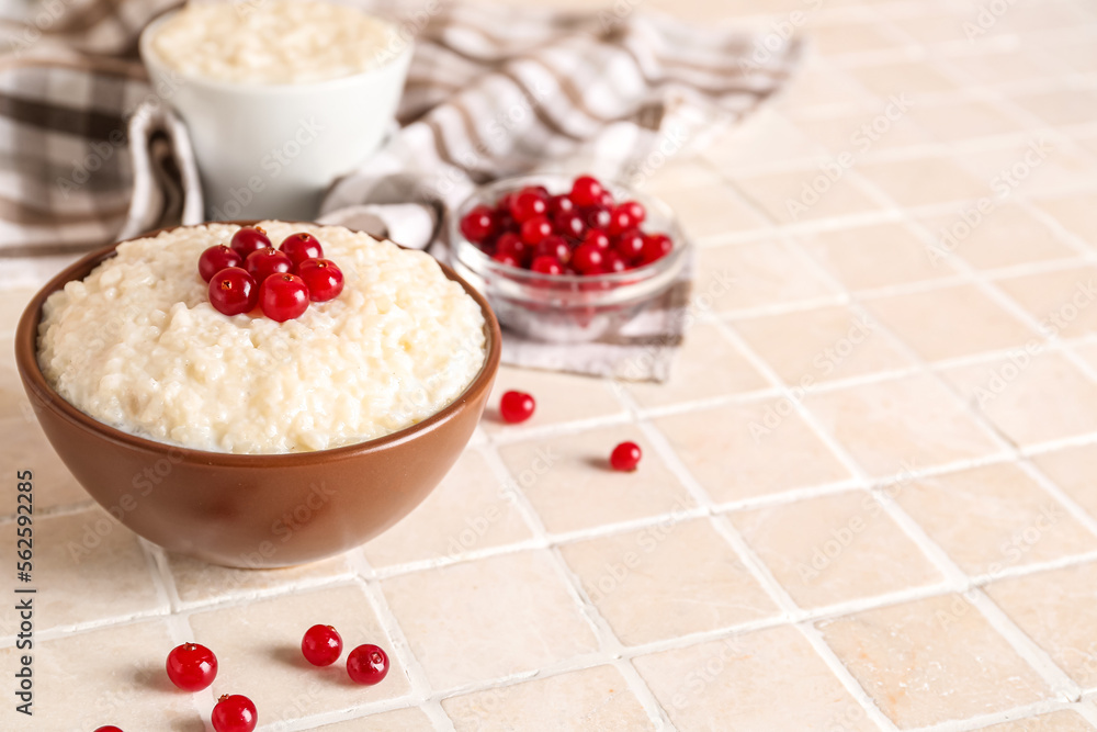 Bowl with delicious rice pudding and cranberry on tile table