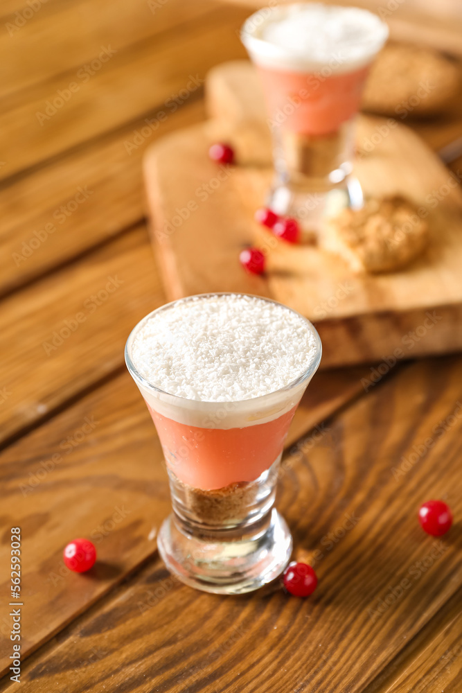 Shot of delicious pudding with coconut shavings and cranberry on wooden table