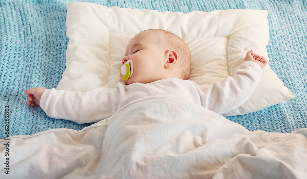 Cute three month old baby sleeping in comfortable bed.