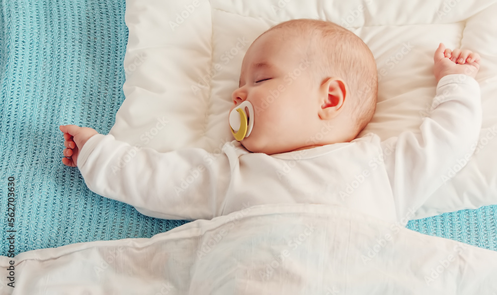 Cute three month old baby sleeping in comfortable bed.