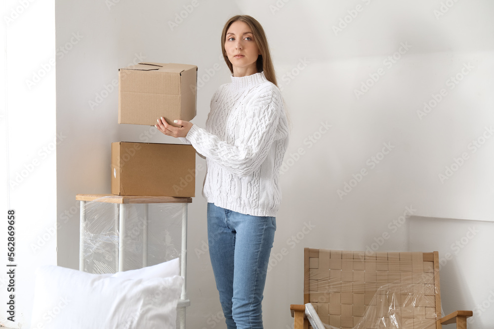 Young woman with cardboard box in bedroom on moving day