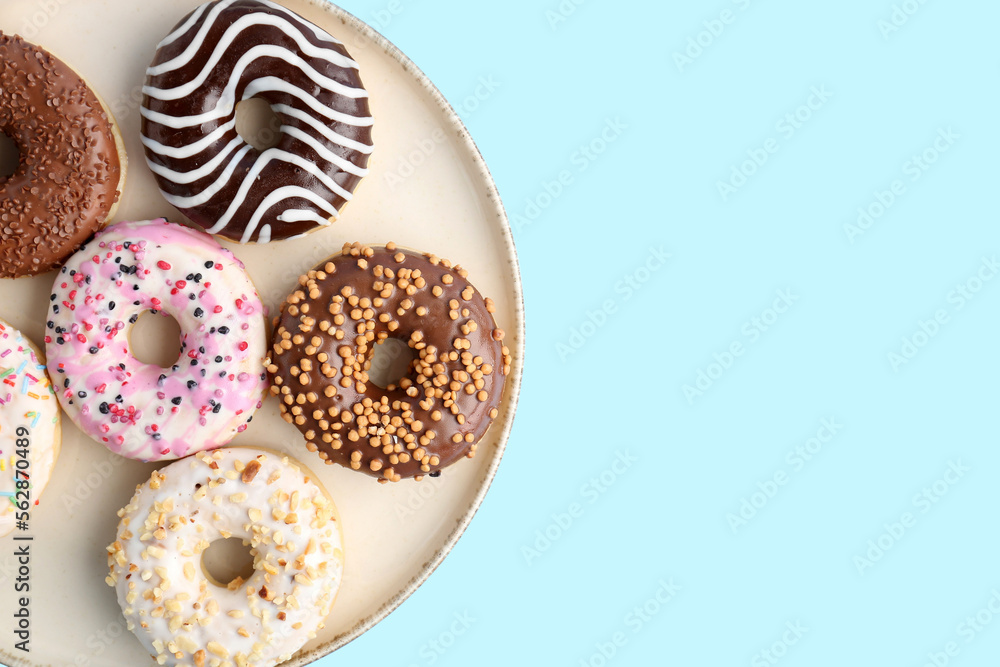 Plate of sweet donuts on color background