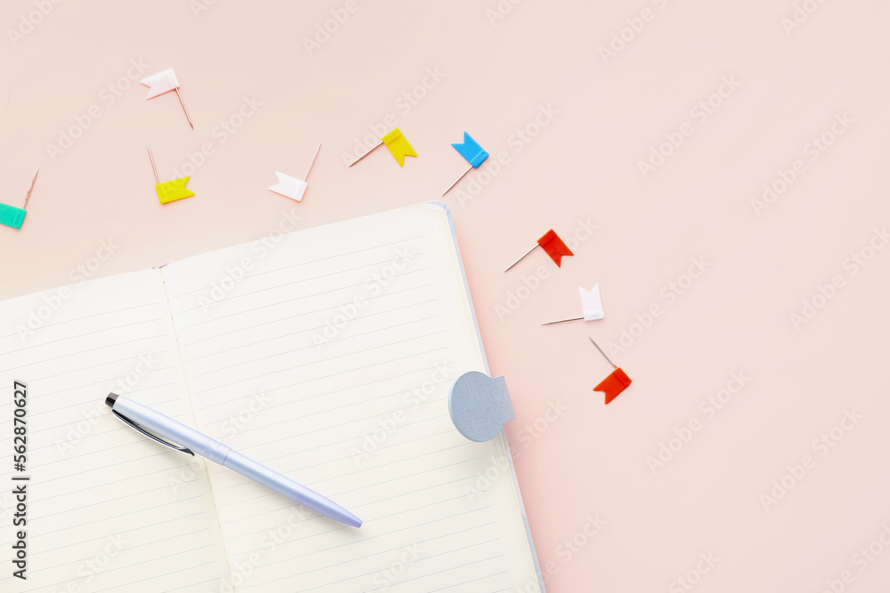 Open notebook, pen and pins on pink background