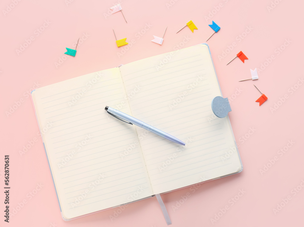 Open notebook, pen and pins on pink background