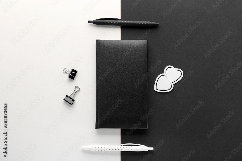 Notebook with pens on black and white background