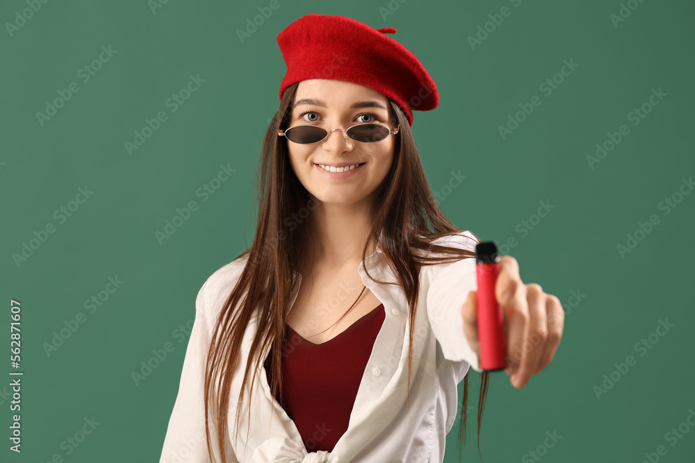 Stylish young woman with disposable electronic cigarette on green background, closeup