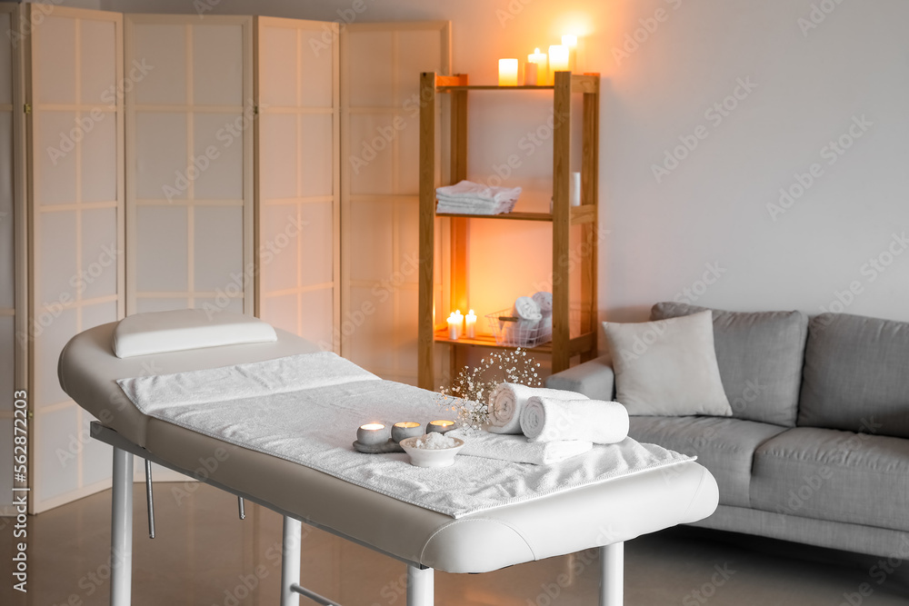 Interior of spa salon with couch, shelving unit and burning candles