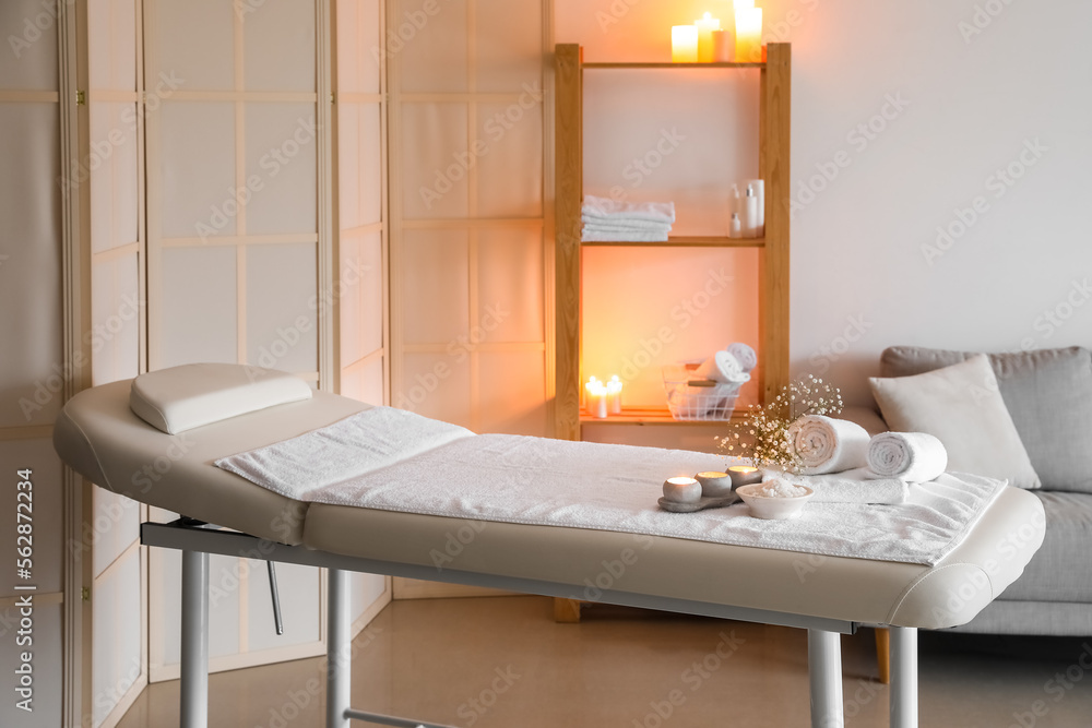 Interior of spa salon with couch, shelving unit and burning candles