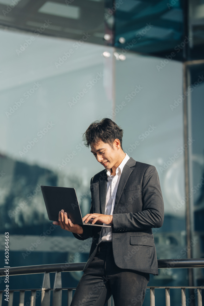 Handsome young manager working on laptop while sitting outdoors on the stairs, concept of work life 