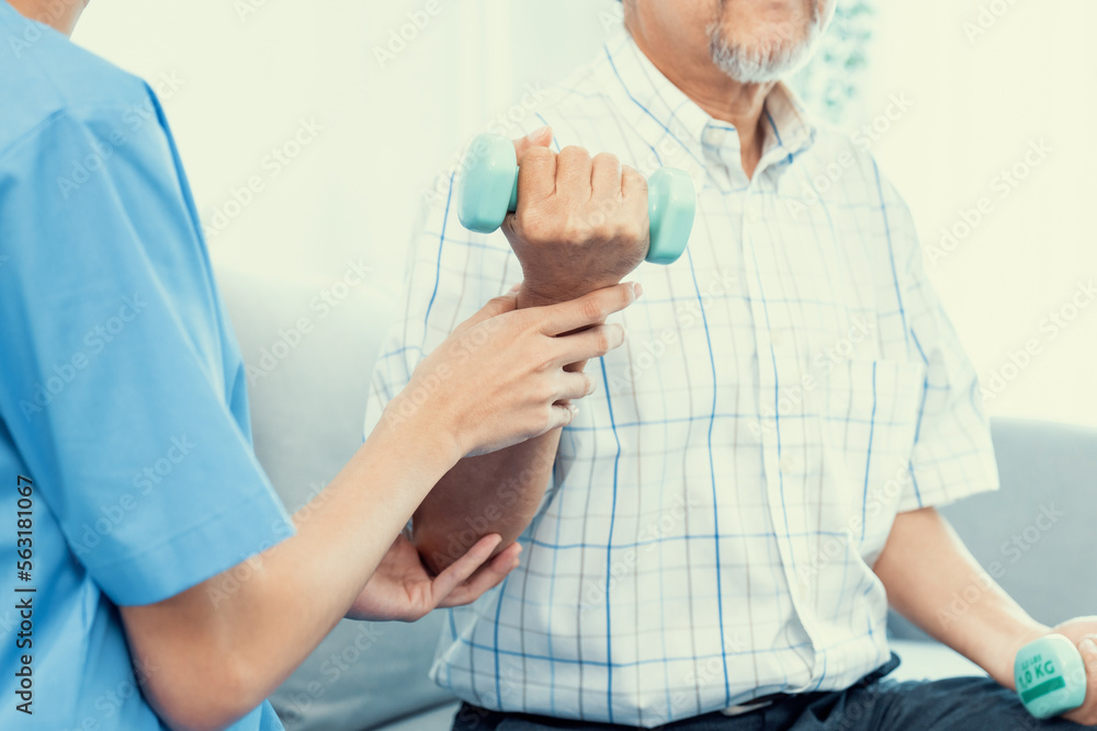 Contented senior patient doing physical therapy with the help of his caregiver. Senior physical ther