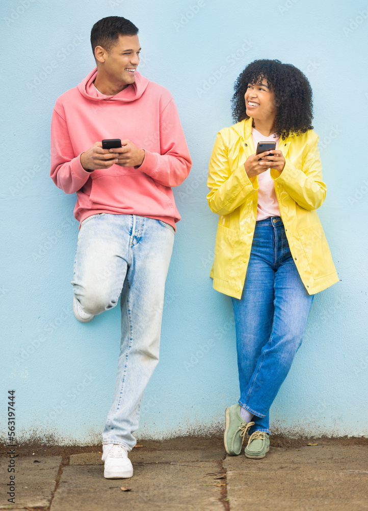 Happy friends, phone and smile leaning on a wall enjoying social media, conversation or communicatio