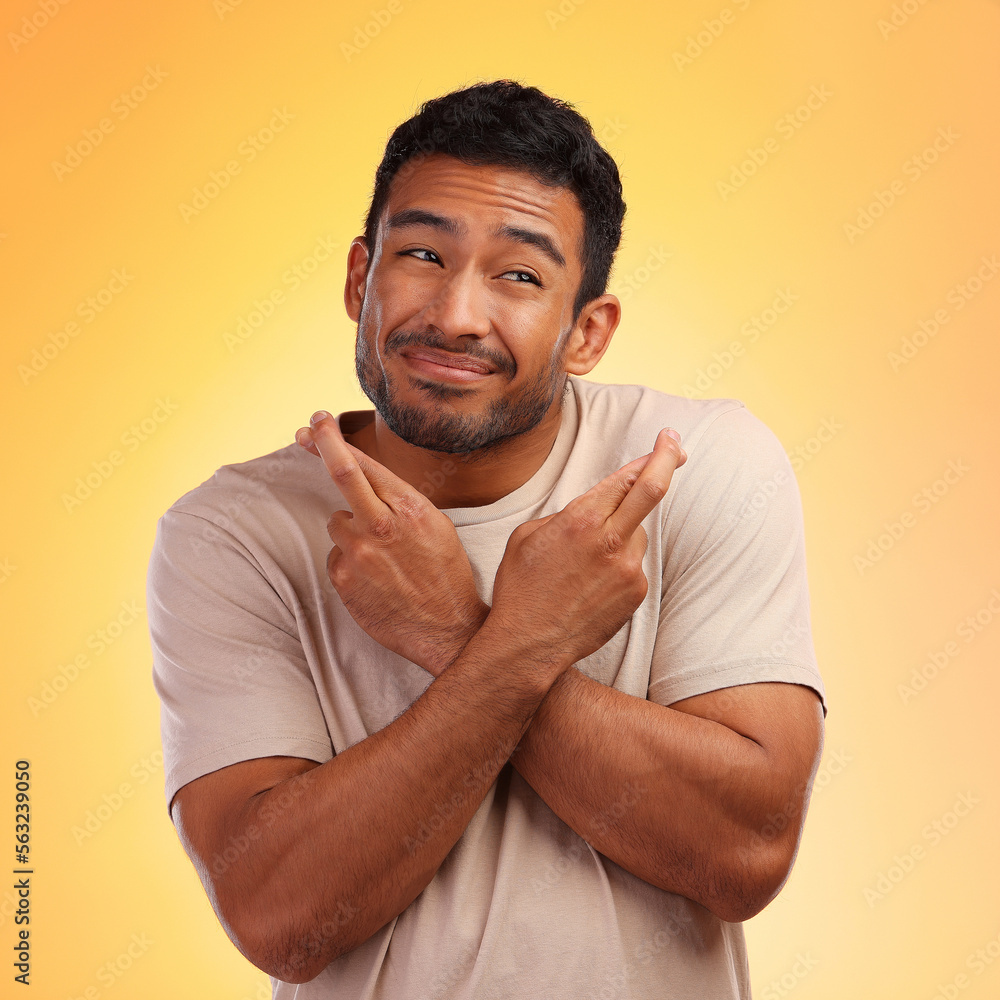 Fingers crossed, man and model with a orange studio background with hand sign for luck. Smile, hope 