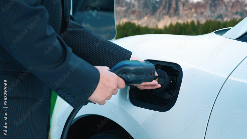 Progressive man recharge electric vehicle installing power cable plug from charging station with rur