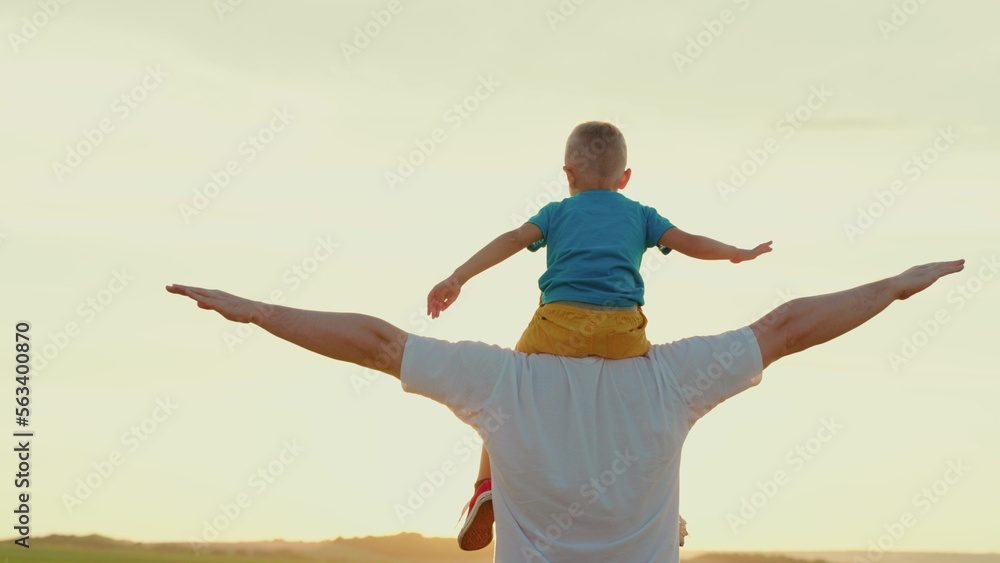 Happy family. A father plays with his son in the park in spring, a malichk sits on his fathers shou