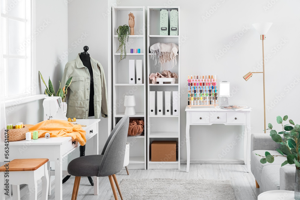 Interior of atelier with tailors workplace, mannequin and shelving unit