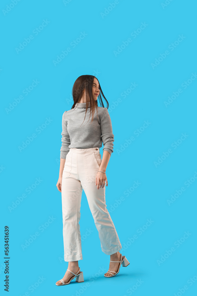 Young woman in grey sweater on blue background