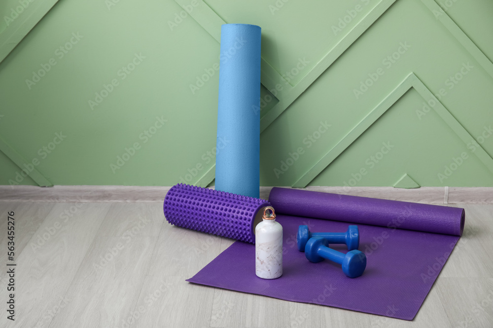 Sports water bottle with equipment on mat near green wall