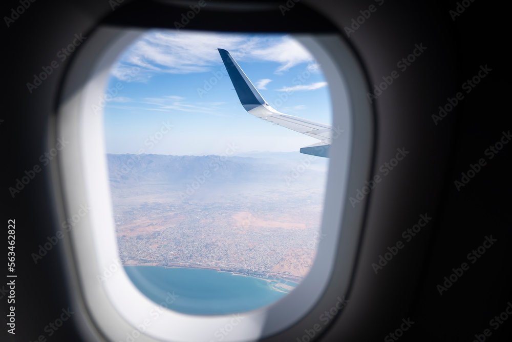 View of aircraft wing and clouds through the porthole.