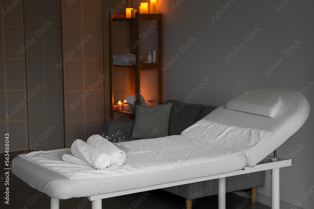 Interior of spa salon with couch, shelving unit and burning candles