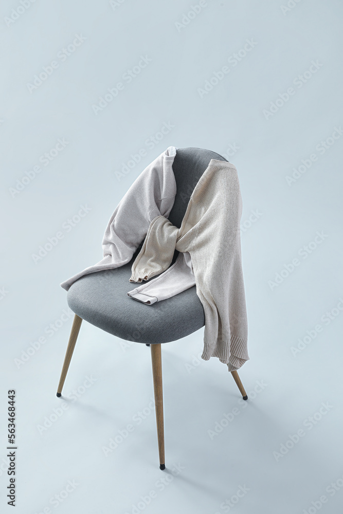 Chair with sweaters on grey background