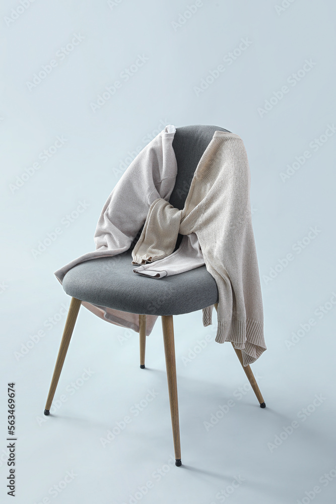 Chair with sweaters on grey background