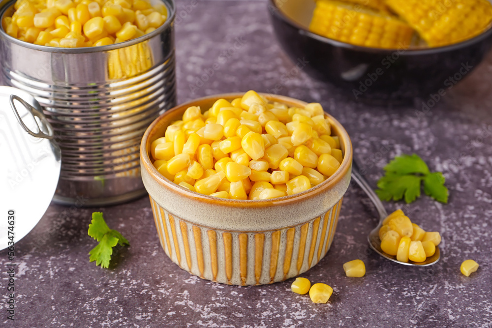 Bowl with corn kernels, tin can and parsley leaves on table