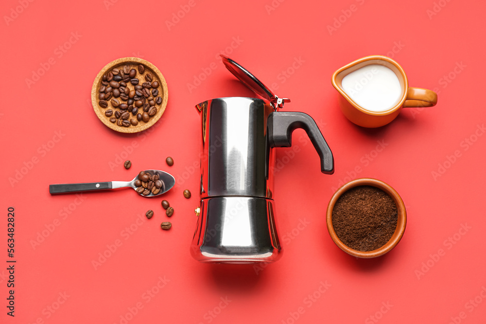 Geyser coffee maker, jug of milk, spoon, beans and melted coffee on red background