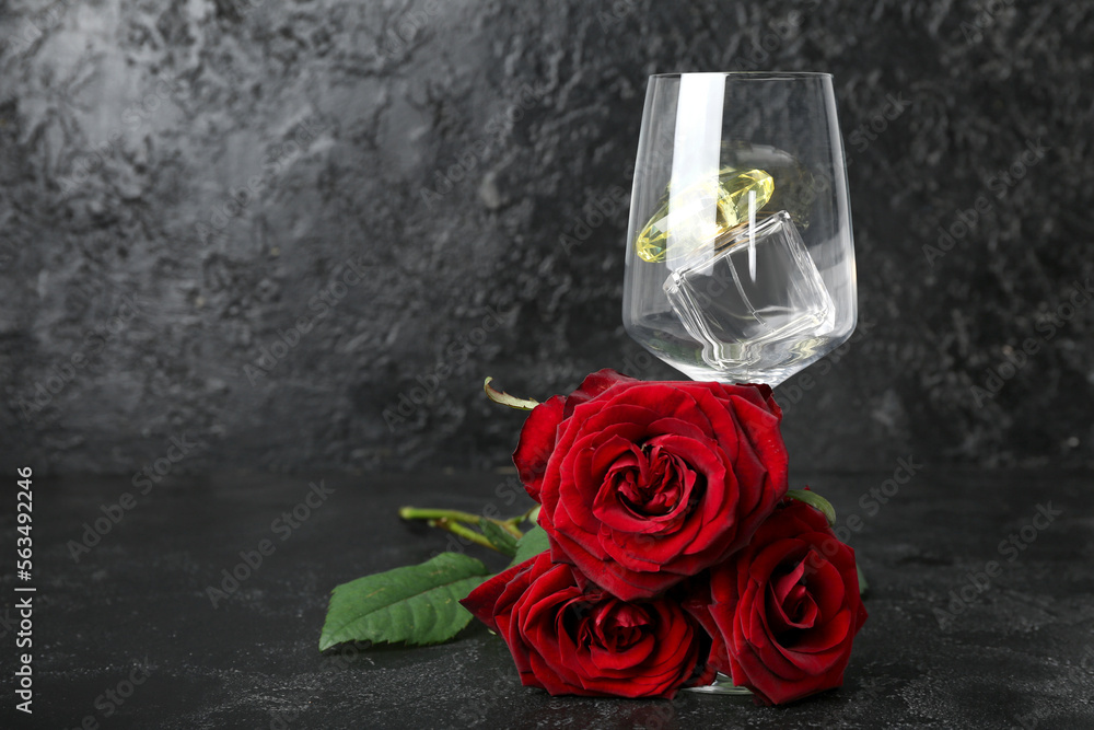 Glass with perfume and roses for Valentines day on dark background