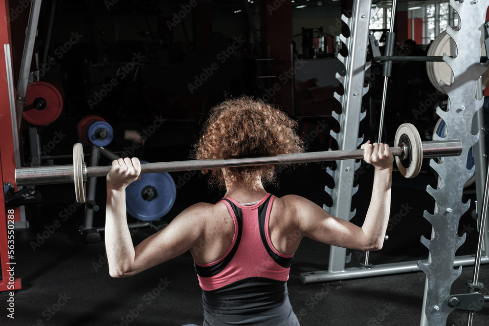 Woman bodybuilder engaged with a barbell in the gym