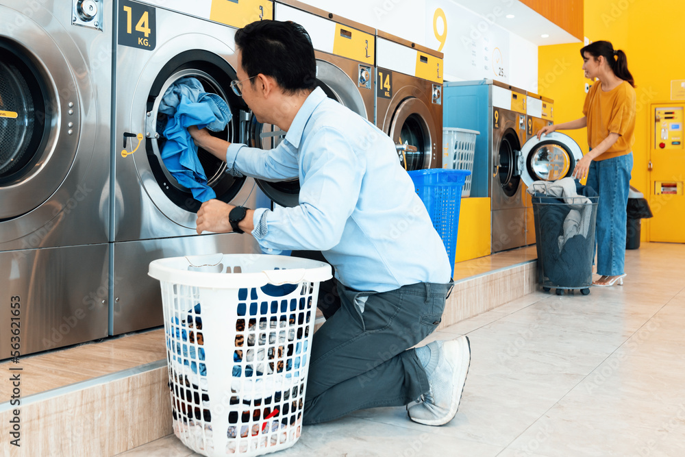 Asian people using qualified coin operated laundry machine in the public room to wash their cloths. 