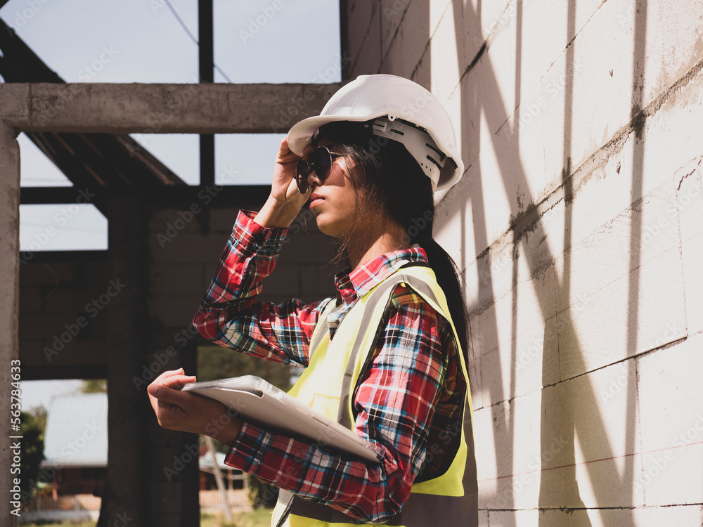 Female engineer with house under construction, brick and steel structure, construction site worker